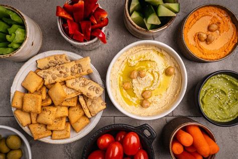 Tabla de presentación con diversos dips, panes y vegetales