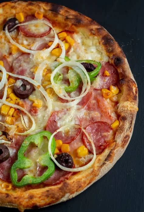Foto de una pizza gigante casera con bordes dorados y diversos toppings