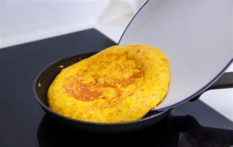 Proceso de voltear la tortilla en la sartén con un plato.