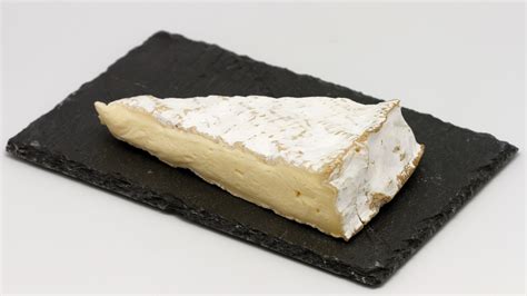 Queso Brie entero y cortado mostrando su corteza y centro cremoso