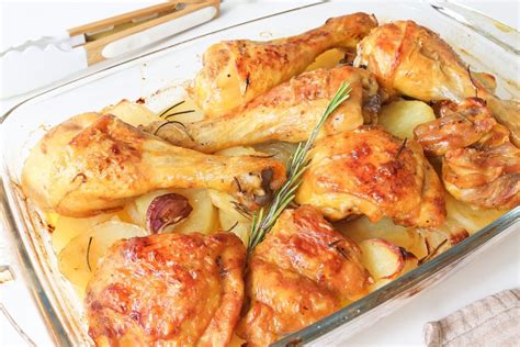 Pollo asado entero con patatas al romero en una fuente de horno