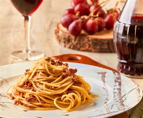Plato de pasta con salsa y botella de vino