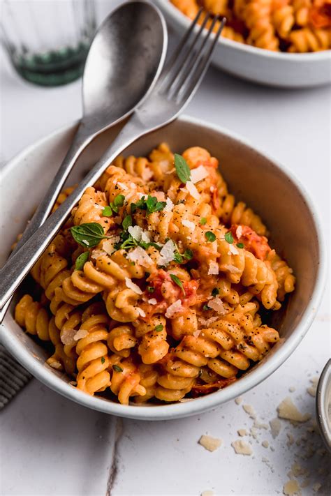 Fotografía cenital de un plato de pasta con salsa de rúcula, nueces y escamas de queso parmesano