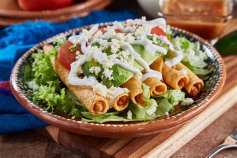 Imagen de un plato de tacos dorados de jamón y queso recién hechos y crujientes
