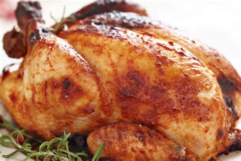 Pollo asado entero recién salido del horno, reposando en una tabla de cortar antes de ser trinchado