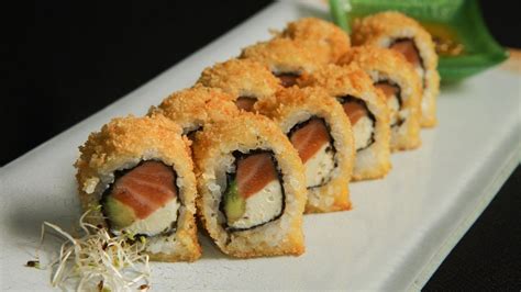 Plato de sushi variado con rolls fritos y nikkei, decorado