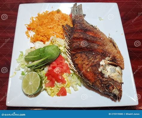 Plato de pescado frito servido con ensalada y acompañamientos