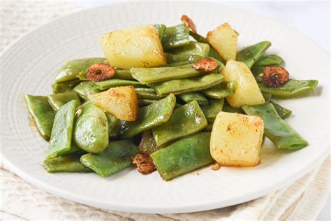 Plato de guiso de judías verdes con patatas y sofrito, listo para servir