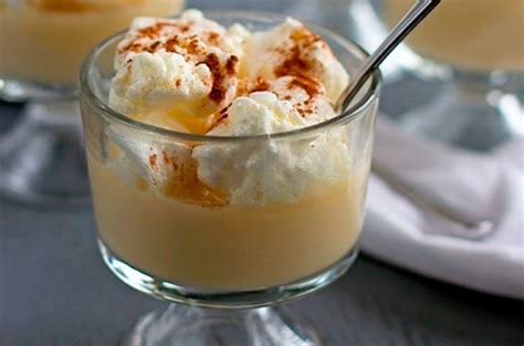 Imagen de un postre Leche Nevada servido en una copa de cristal, mostrando la textura cremosa de la leche y los copos de merengue flotando, decorado con un toque de canela.