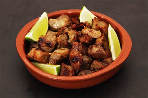 Plato de masas de cerdo fritas doradas y crujientes servidas con cebollas y acompañamientos tradicionales.