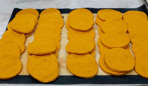 Sopaipillas crudas separadas con papel para congelar