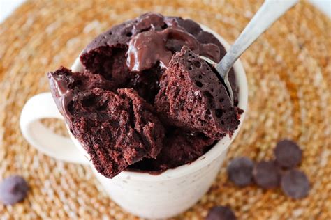 Foto de un mug cake de chocolate keto recién hecho, humeante en una taza, decorado con frutos rojos.