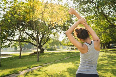 Mujer en etapa de menopausia sonriente, haciendo ejercicio ligero al aire libre, simbolizando bienestar y salud