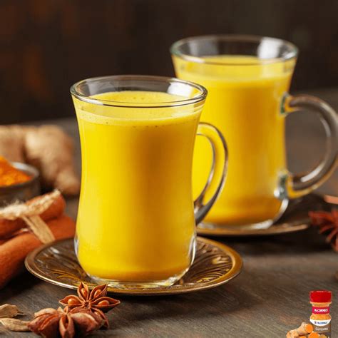 Vaso de leche dorada con especias flotando y una cuchara