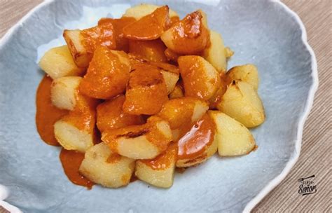 Patatas bravas servidas con salsa vegana, una parte fritas y otra al horno