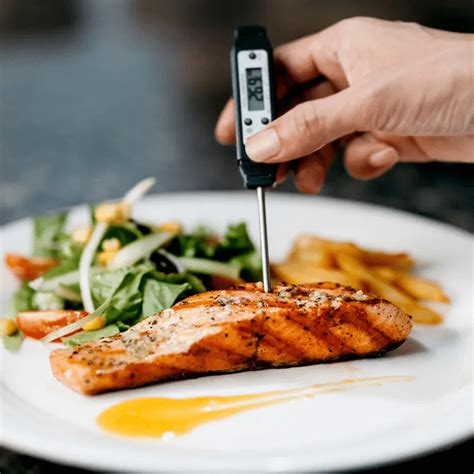 Persona utilizando un termómetro de cocina para verificar la temperatura interna de un alimento