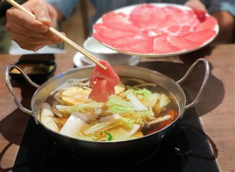 Mesa con olla de shabu-shabu y platos de ingredientes crudos
