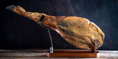 Imagen de un jamón entero colgado en una despensa con buena ventilación.