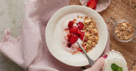 Foto de una persona comiendo yogur con cereal para el desayuno