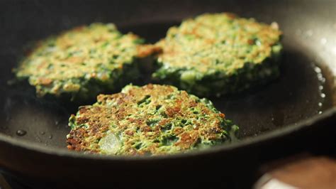 Una sartén con tortitas de espinacas dorándose a fuego medio