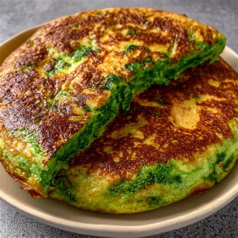 Una tortilla española de espinacas dorada, cortada en porciones, servida con perejil picado y sal marina