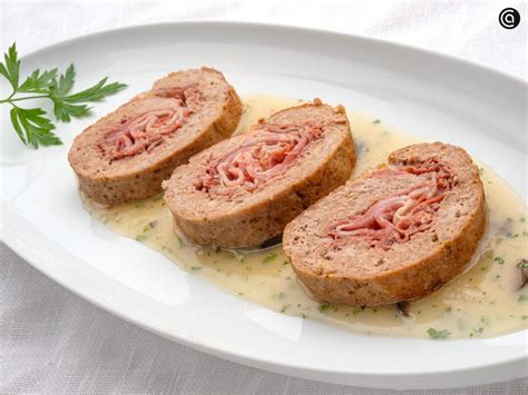 Imagen de un rollo de carne dorado y recién cortado mostrando el relleno de jamón y queso fundido