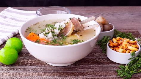 Fotografía de un caldo de cordero peruano servido en plato hondo con hierbas aromáticas frescas