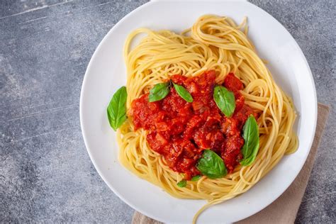 Fotografía de un plato de pasta con salsa de tomate casera y verduras
