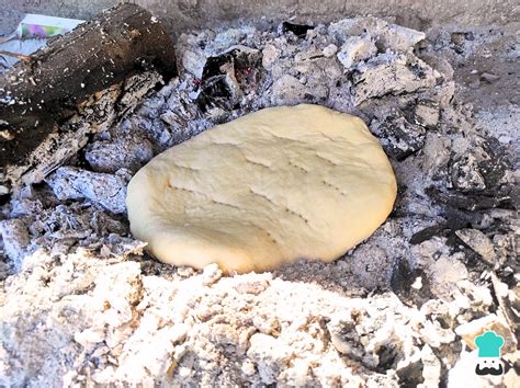 Fotografía detallada de una tortilla al rescoldo recién retirada de las brasas, mostrando su textura ahumada