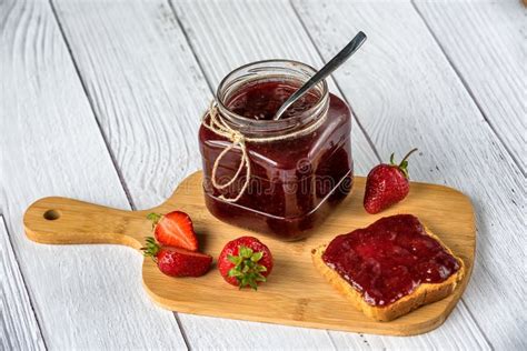 Foto de mermelada de fresa casera en un frasco de vidrio, con fresas frescas alrededor
