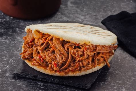 Arepas rellenas de carne mechada, queso y caraotas negras en un plato