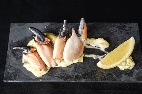 Fotografía profesional de pinzas de jaiba servidas en un plato elegante con guarnición de hierbas frescas