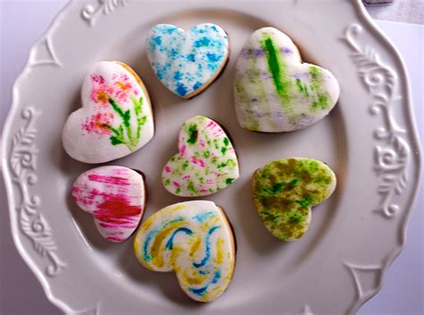 Galletas decoradas pintadas a mano con pincel, mostrando varios diseños coloridos y artísticos.