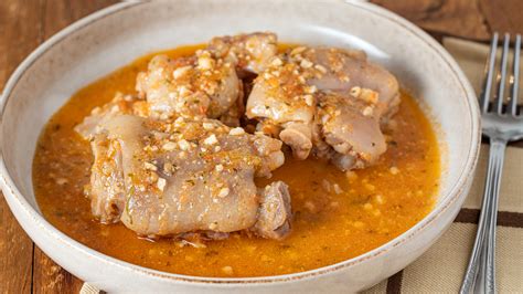 Fotografía de un plato de manitas de cerdo guisadas en salsa servidas en cazuela de barro