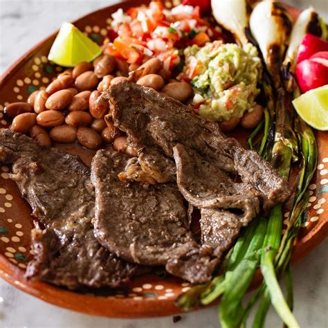 Plato de carne asada con diversas guarniciones coloridas