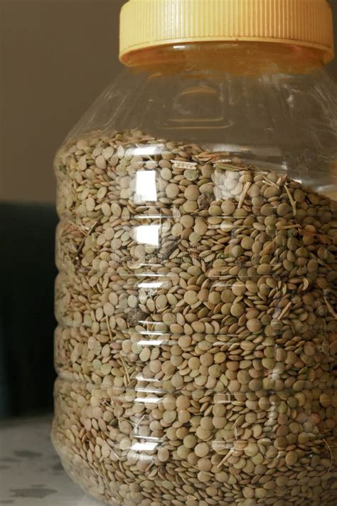 Imagen de un recipiente hermético con lentejas secas almacenado en una despensa.
