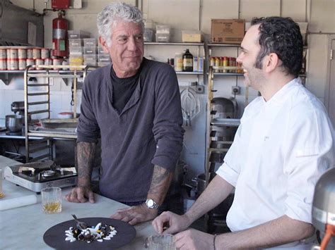 Anthony Bourdain en una cocina de restaurante, supervisando a su equipo con una expresión intensa