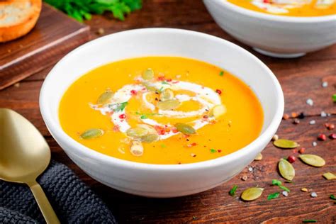 Sopa de calabaza cremosa sin lácteos en un tazón rústico con hierbas