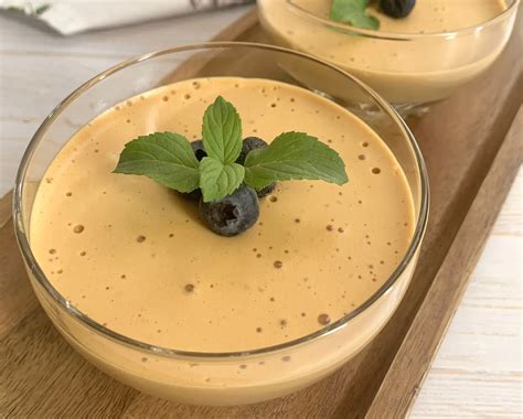 Mousse de manjar servido en copas individuales con decoración de frutos rojos y chocolate