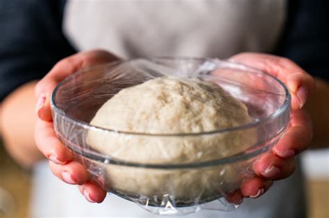 Masa de pan levándose en un bol cubierto con film transparente