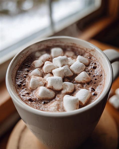 Una taza de chocolate caliente cremoso con malvaviscos en un ambiente acogedor de invierno