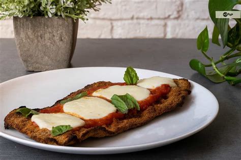 Fotografía profesional de una milanesa a la napolitana recién salida del horno con el queso fundido y dorado