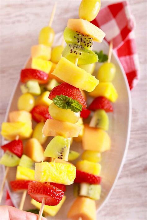 Persona montando brochetas de fruta con palillos de madera