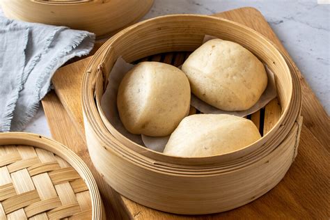 Foto de Mantou: panecillos al vapor blancos y esponjosos en una vaporera de bambú.