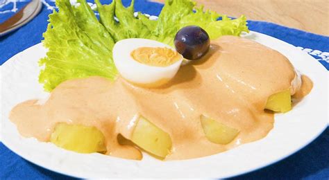 Fotografía gastronómica de una crema de rocoto servida sobre papas cocidas con una presentación atractiva.