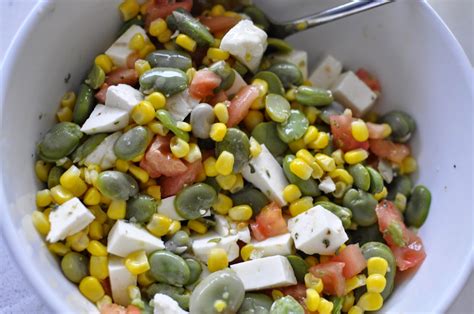 Primer plano de ensalada de habas frescas con cebolla tierna, tomates y hierbas frescas