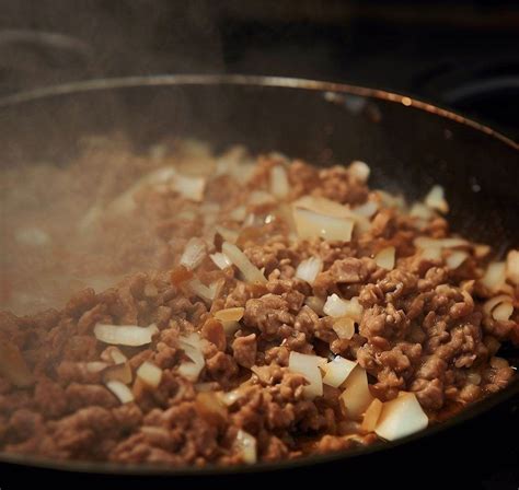 Preparación del relleno de chopped cheese en una sartén, con la carne picada y el queso derritiéndose.