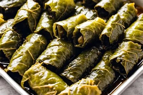 Hojas de parra rellenas cocinándose en una olla con rodajas de limón y un plato para presionar