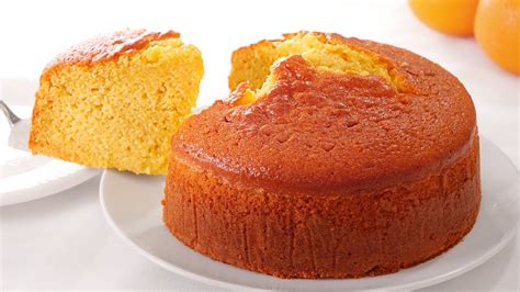 Fotografía profesional de un bizcochuelo de naranja esponjoso decorado con rodajas de naranja sobre una mesa de madera