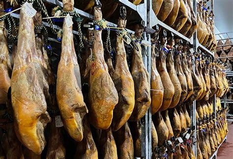 Jamón serrano colgado con chorrera recogiendo la grasa en una tienda